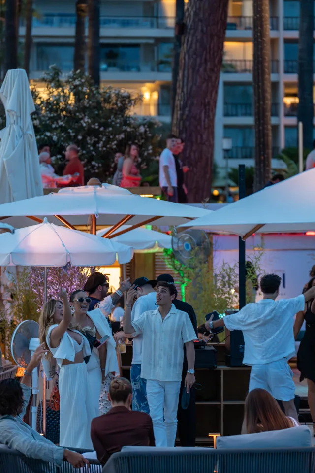 Guests dancing beneath white umbrellas at a beachside evening gathering