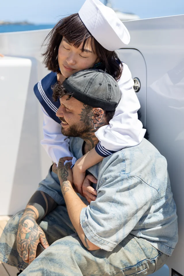A child in a sailor outfit embracing a seated man on a boat